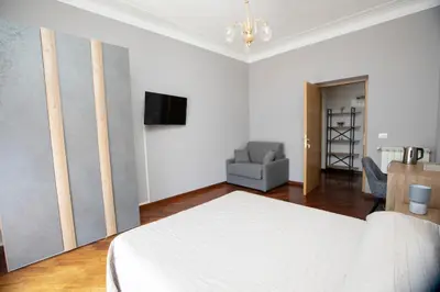 a white bedroom with a bed and a chair at Relais Rosselli in Rome