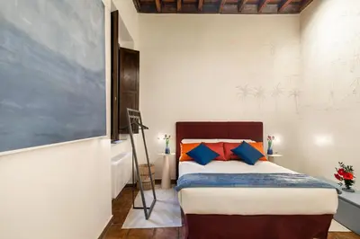 a bedroom with a bed with blue and orange pillows at Elegant Apartment Minelli Navona by GHOR in Rome