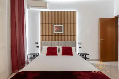 a bedroom with a white bed with two red pillows at Teano Apt - 10min to Colosseo, 100mt to metro, A-C, 2 Bedrooms in Rome