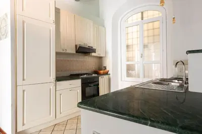 a kitchen with white cabinets and a black counter top at Trastevere Charming Apartment by RomeLoft in Rome