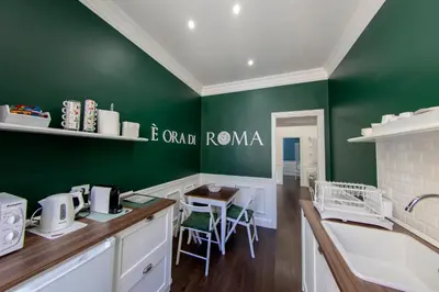 a kitchen with green walls and a table and chairs at PapaRoma Suite in Rome