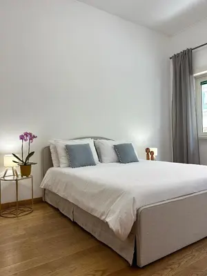 a white bedroom with a large bed with blue pillows at MarVal Vatican House in Rome