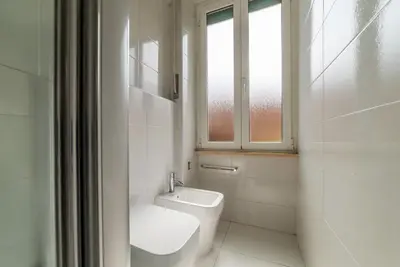a white bathroom with a toilet and a window at GuestHost - Bright Flat in Lungotevere Flaminio in Rome