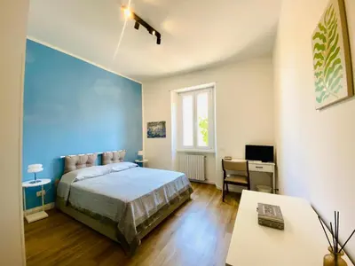 a bedroom with a blue wall and a bed and a desk at Domus 14 in Rome