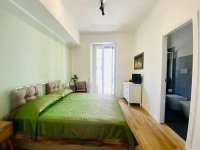 a bedroom with a green bed and a bathroom at Domus 14 in Rome