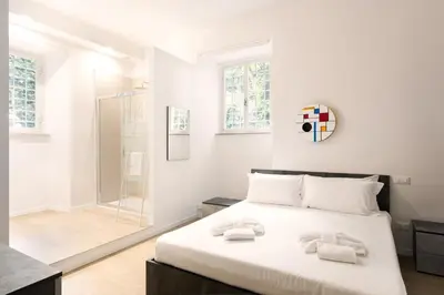 a white bedroom with a bed and a glass shower at Aventino Urban Place by One Up Hospitality in Rome