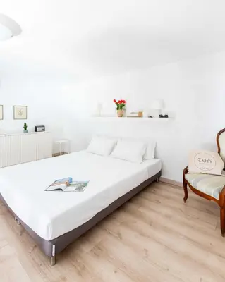 a white bedroom with a large bed and a chair at Mini apartment Cairoli 1 - Zeno 42 in Rome