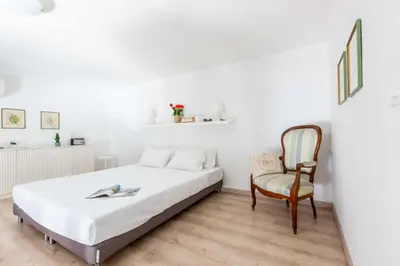 a white bedroom with a bed and a chair at Mini apartment Cairoli 1 - Zeno 42 in Rome