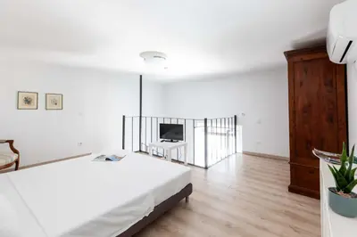 a white bedroom with a bed and a television at Mini apartment Cairoli 1 - Zeno 42 in Rome