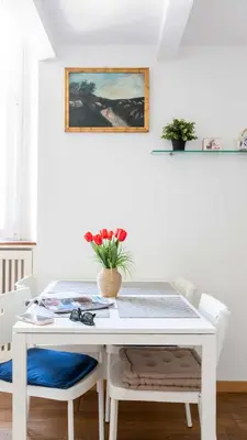 a white dining room table with two chairs and a vase of flowers at Mini apartment Cairoli 2 - Zeno 42 in Rome