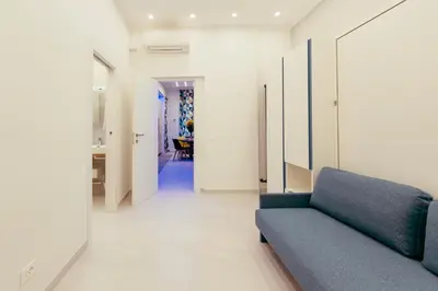 a living room with a blue couch and a hallway at 30' Walk Vatican & Stadium Art, Smart Home in Rome