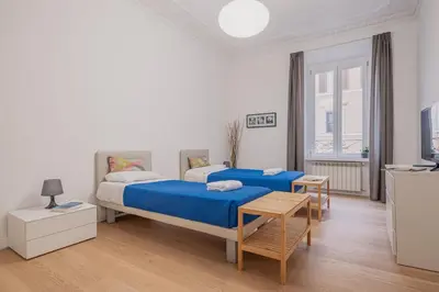 a white bedroom with two beds and a television at Life Home Vatican in Rome