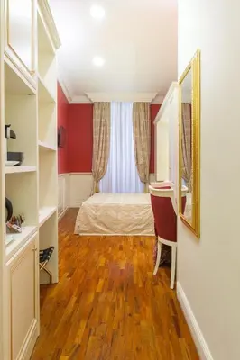 a bedroom with a bed and a desk and a mirror at Dimora Frattina in Rome