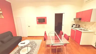 a living room with a table and a kitchen at Dimora Frattina in Rome