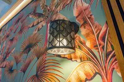 a lamp hanging on a wall with a mural of plants at Trasteverina Apartment in Rome