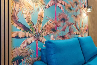 a blue couch in a room with a mural of palm trees at Trasteverina Apartment in Rome