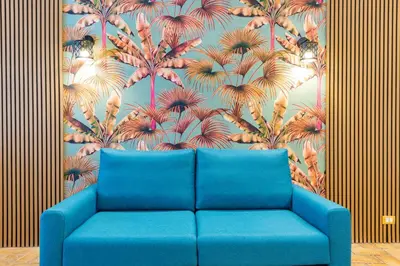 a blue couch in front of a wall with a mural of palm trees at Trasteverina Apartment in Rome