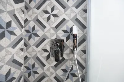 a bathroom with a geometric tile wall and a door at Linda Apartment in Rome