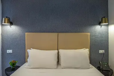 a bedroom with a bed with two pillows and a headboard at Essence Collection Hotel in Rome