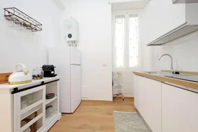 a white kitchen with a sink and a refrigerator at Makà 32 in Rome
