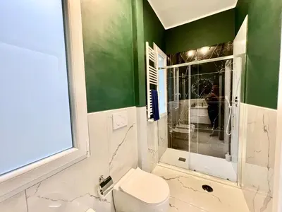 a bathroom with a toilet and a green wall at Stylish Apartment near Trastevere in Rome