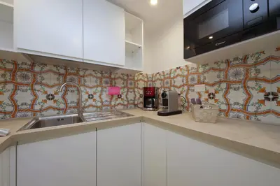 a kitchen with white cabinets and a tile wall at MM Trevi Apartment in Rome