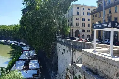 a street sign next to a river with boats at Nido degli Artisti in Trastevere Piazza Trilussa in Rome
