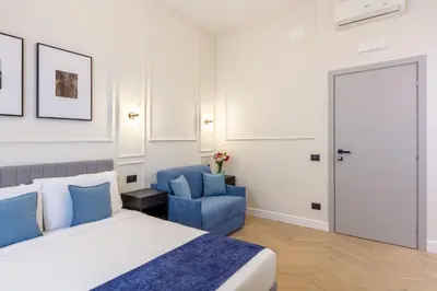 a bedroom with a bed and a blue chair at Piazza del Popolo Boutique GuestHouse in Rome
