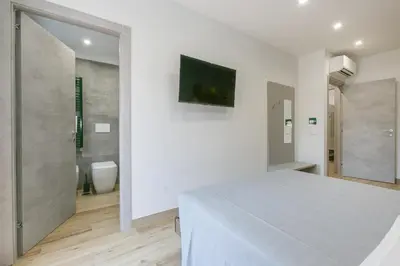 a white bedroom with a bed and a bathroom at Roma Vaticano Deluxe in Rome