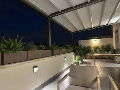 a rooftop patio with a table and chairs at night at Beautiful Penthouse Roma in Rome