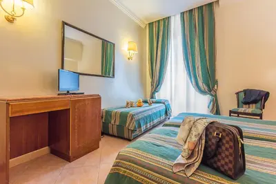 a hotel room with two beds and a desk and a mirror at Raeli Hotel Siracusa in Rome