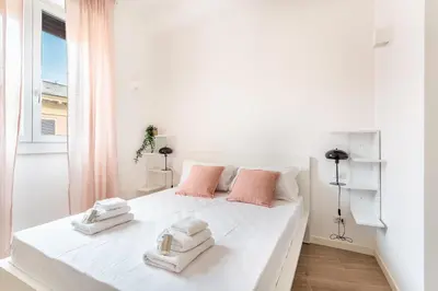 a white bedroom with a large white bed with towels on it at iFlat Stylish New Flat Steps from the Vatican in Rome