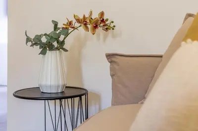 a vase with flowers on a table next to a bed at iFlat Stylish New Flat Steps from the Vatican in Rome