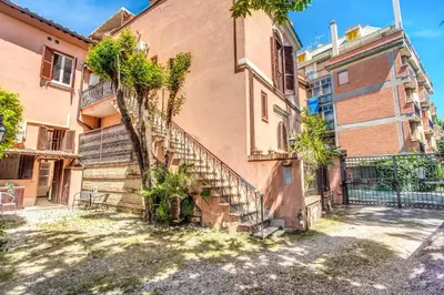 an old building with stairs and trees in front of it at Link Campus Apartment in Rome