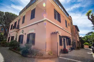 a large pink building on a cobblestone street at Link Campus Apartment in Rome