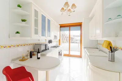a kitchen with white cabinets and a red chair at 85mq of Vintage Luxury-Near Vatican City WIFI AC in Rome