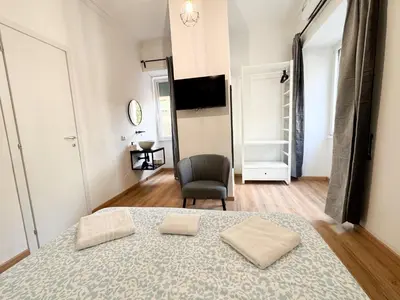 a bedroom with a bed and a chair and a television at Riboty Boutique Rooms in Rome