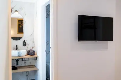 a bathroom with a sink and a tv on a wall at Romart Luxury Rooms in Rome