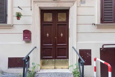 a brown door on a white building with stairs at Gianicolo Maison nel cuore di Roma in Rome