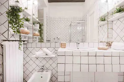 a white tiled bathroom with a sink and a toilet at Gianicolo Maison nel cuore di Roma in Rome