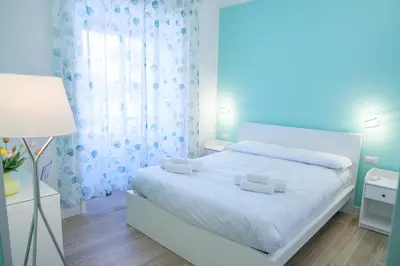 a white bedroom with a white bed and a lamp at RainbHome Colourful Roman Suites in Rome