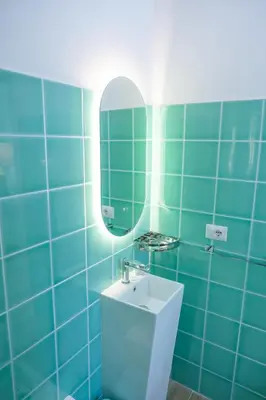 a blue tiled bathroom with a sink and a mirror at RainbHome Colourful Roman Suites in Rome
