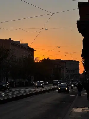 a city street with cars on the road at sunset at Residenza Labicana few steps from Colosseum in Rome