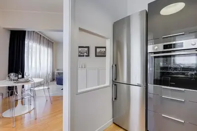 a kitchen with a stainless steel refrigerator and a table at Il Sogno di Balduina a 1 min Stazione Appiano-Ospedale Gemelli in Rome