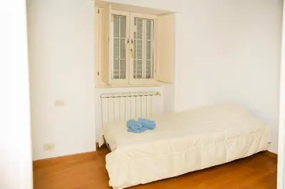 a white bedroom with a bed with a blue towel on it at Tempietto del Carmelo in Rome