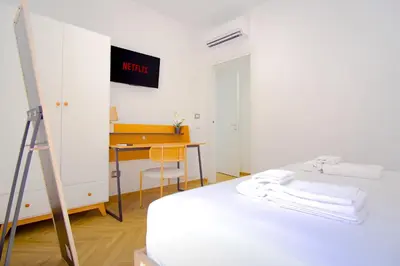 a white room with a bed and a desk at Elegantis Gracchi Apartment - Your Chic Retreat in Central Rome - Vatican Area in Rome