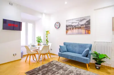 a living room with a blue chair and a table at Elegantis Gracchi Apartment - Your Chic Retreat in Central Rome - Vatican Area in Rome