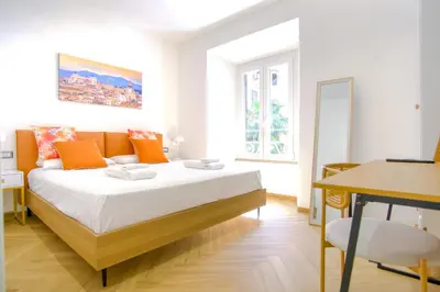 a bedroom with a large bed with orange pillows at Elegantis Gracchi Apartment - Your Chic Retreat in Central Rome - Vatican Area in Rome