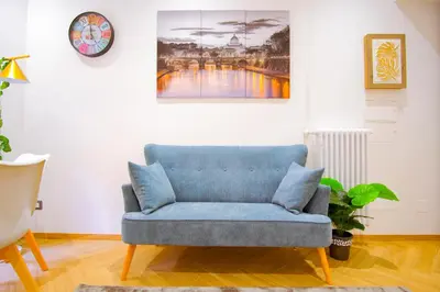 a blue couch in a living room with a clock at Elegantis Gracchi Apartment - Your Chic Retreat in Central Rome - Vatican Area in Rome