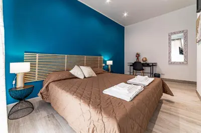 a bedroom with a large bed with a blue wall at Michelangelo Luxury Rooms - Colosseo - WiFi in Rome